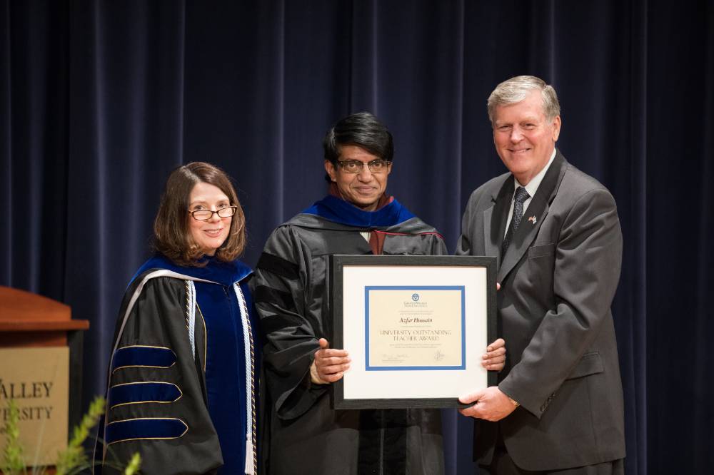 Azfar Hussain holding up his certificate next to President Emeritus Haas and Provost Cimitile.